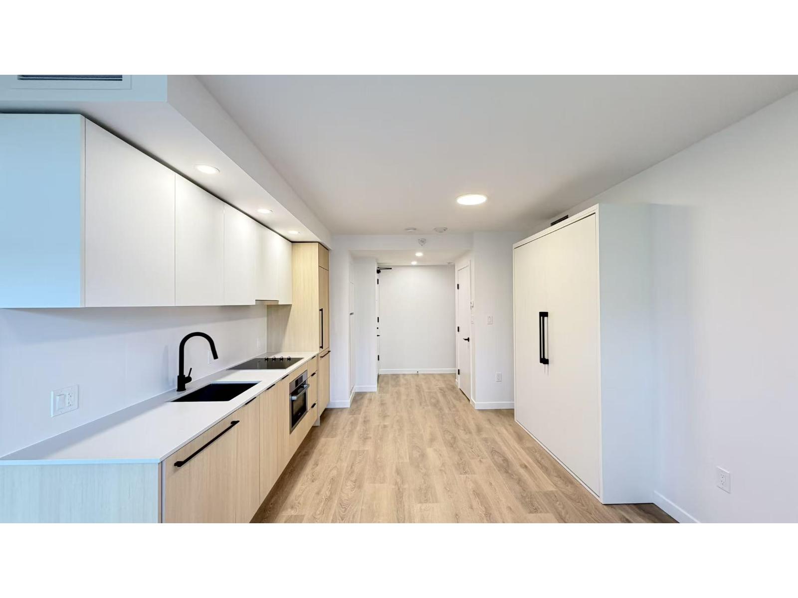 A modern kitchen with wooden floors and white walls.