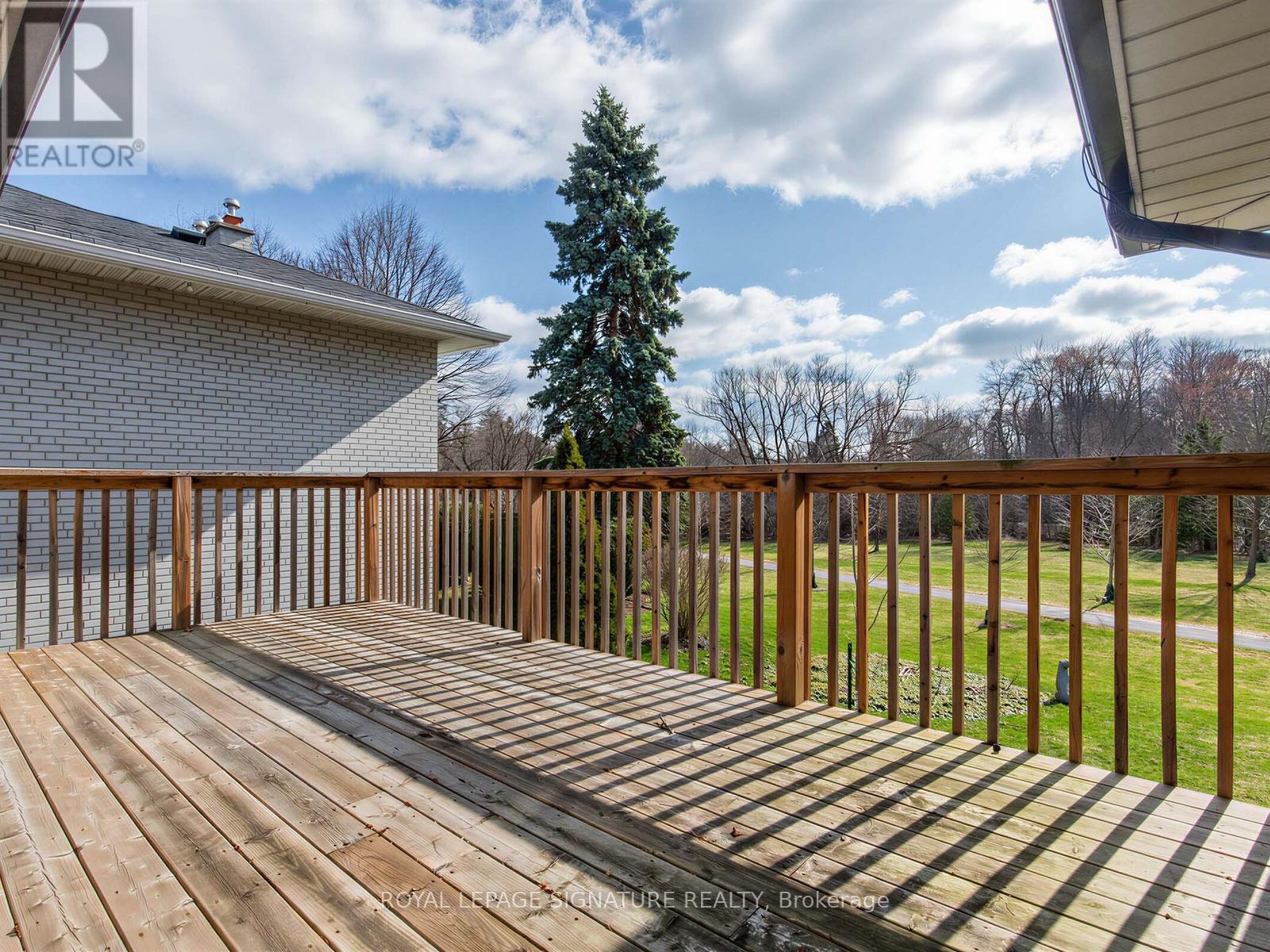 A wooden deck with a house and trees in the background.