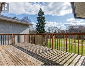 A wooden deck with a house and trees in the background.