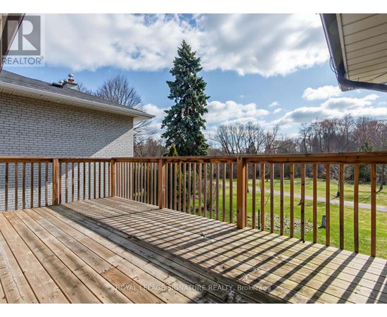 A wooden deck with a house and trees in the background.