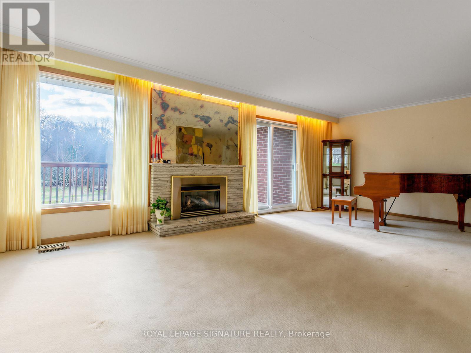 A spacious living room with a fireplace and a painting on the wall.