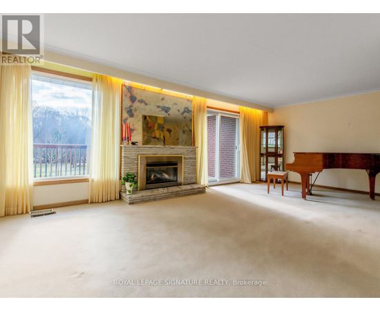 A spacious living room with a fireplace and a painting on the wall.