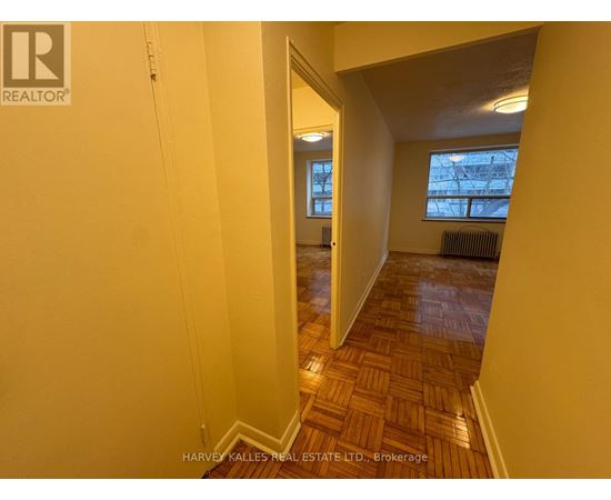 A hallway with a wooden floor and a window with a view of a building outside.