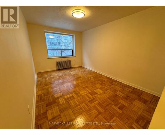 A room with wooden flooring and a window with a view of a building outside.