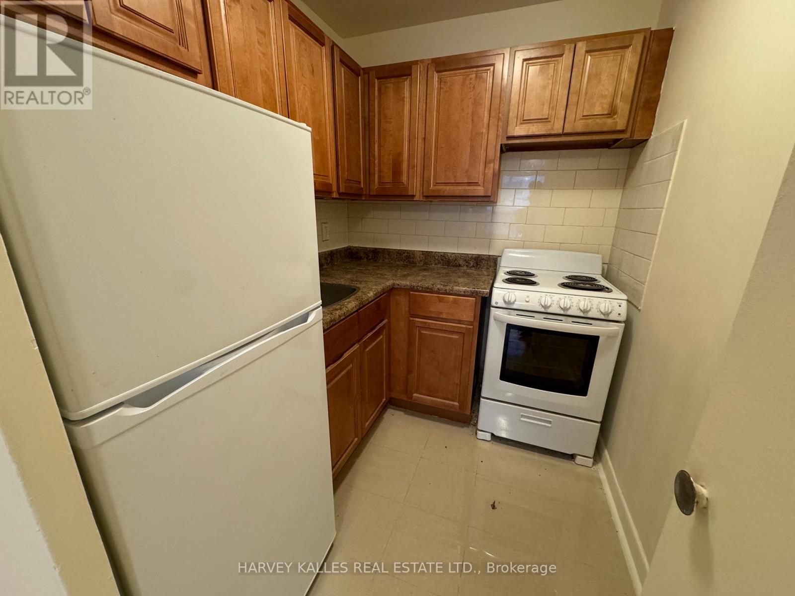 A kitchen with a white fridge, white stove and wooden cabinets.