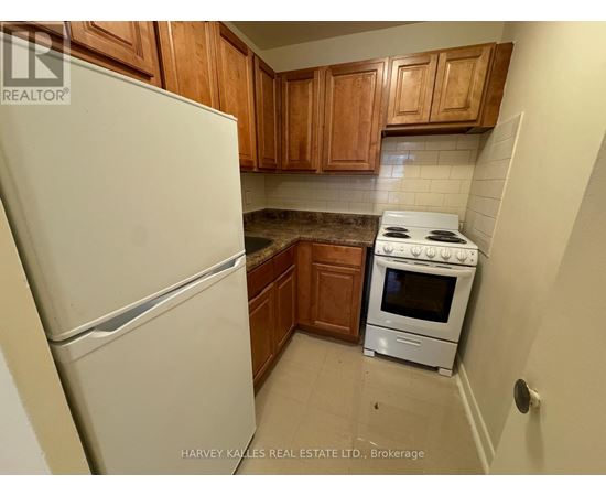A kitchen with a white fridge, white stove and wooden cabinets.