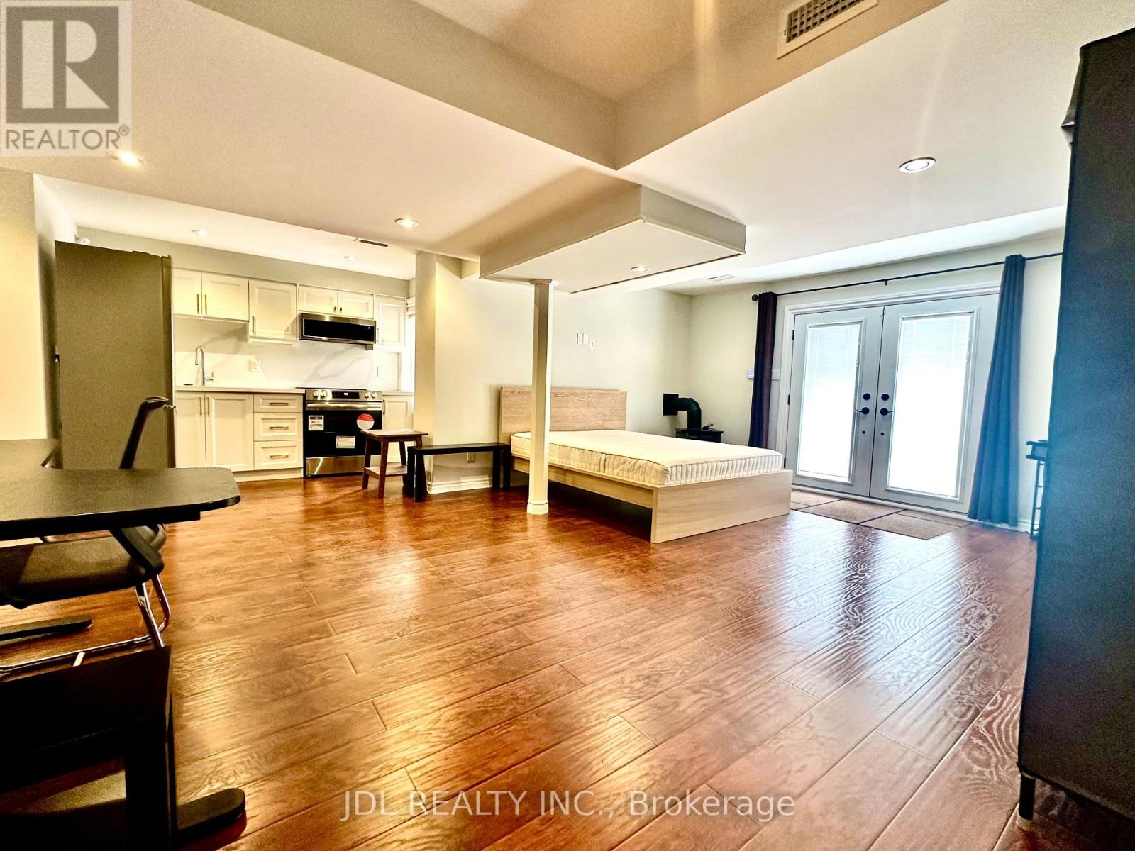A spacious room with wooden flooring and a bed in the corner.