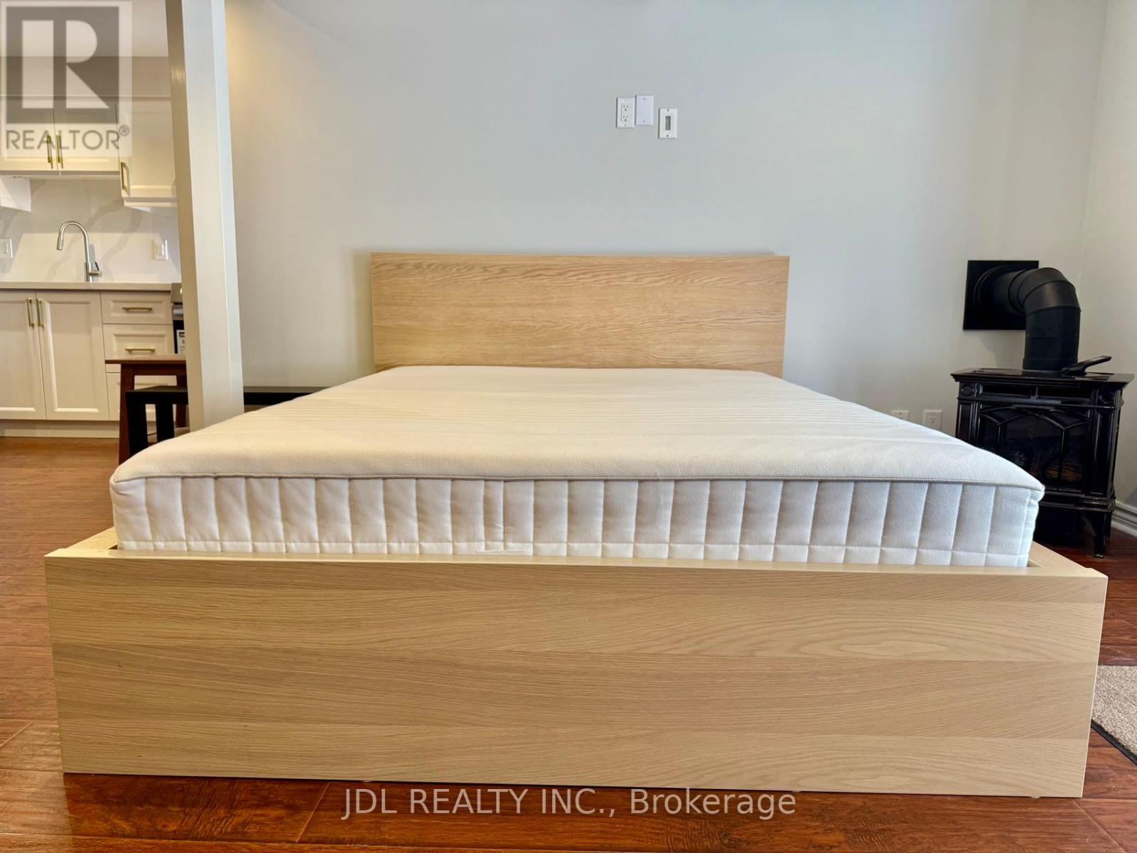 A bed with a wooden frame and mattress in a room.