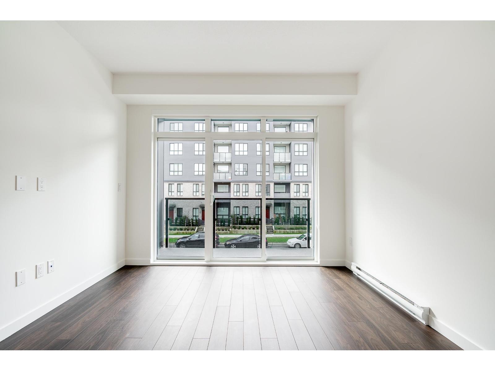 A room with a large window and wooden flooring.
