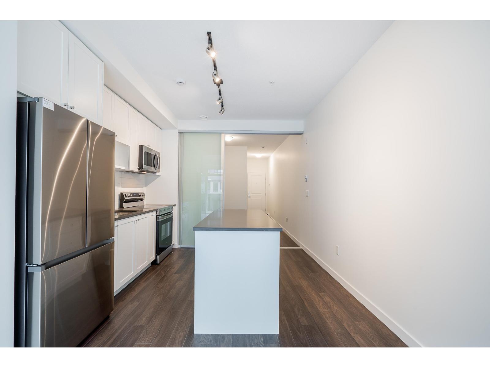 A kitchen with a stainless steel refrigerator and white cabinets.