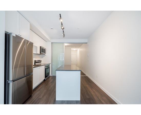 A kitchen with a stainless steel refrigerator and white cabinets.