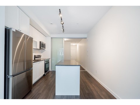 A kitchen with a stainless steel refrigerator and white cabinets.