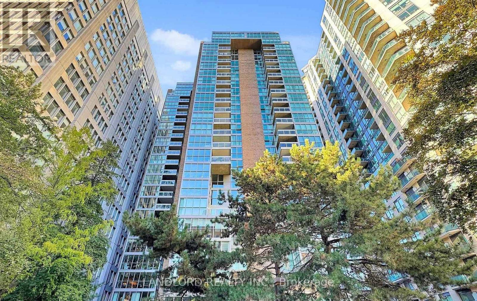 A tall building with a blue glass facade stands between two other buildings.