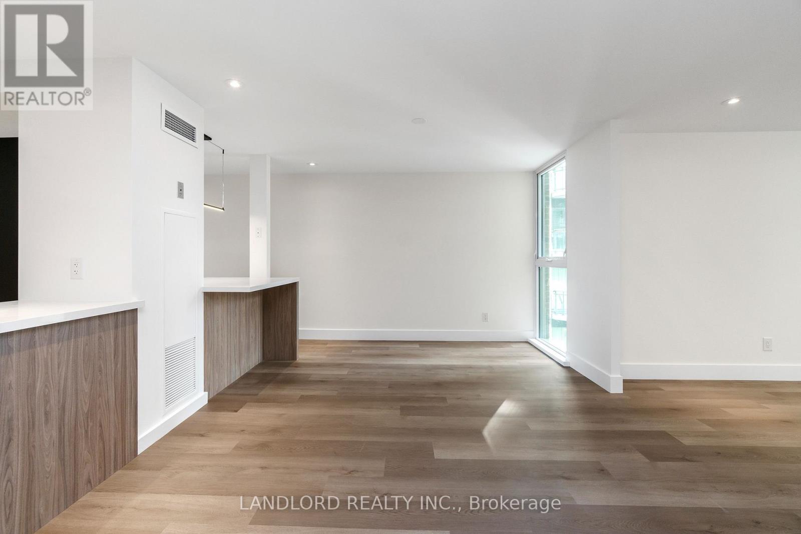 A spacious room with wooden flooring and white walls, presented by Landlord Realty Inc., Brokerage.