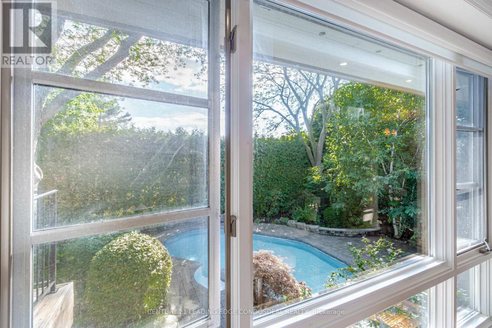 A window with a view of a pool and trees.
