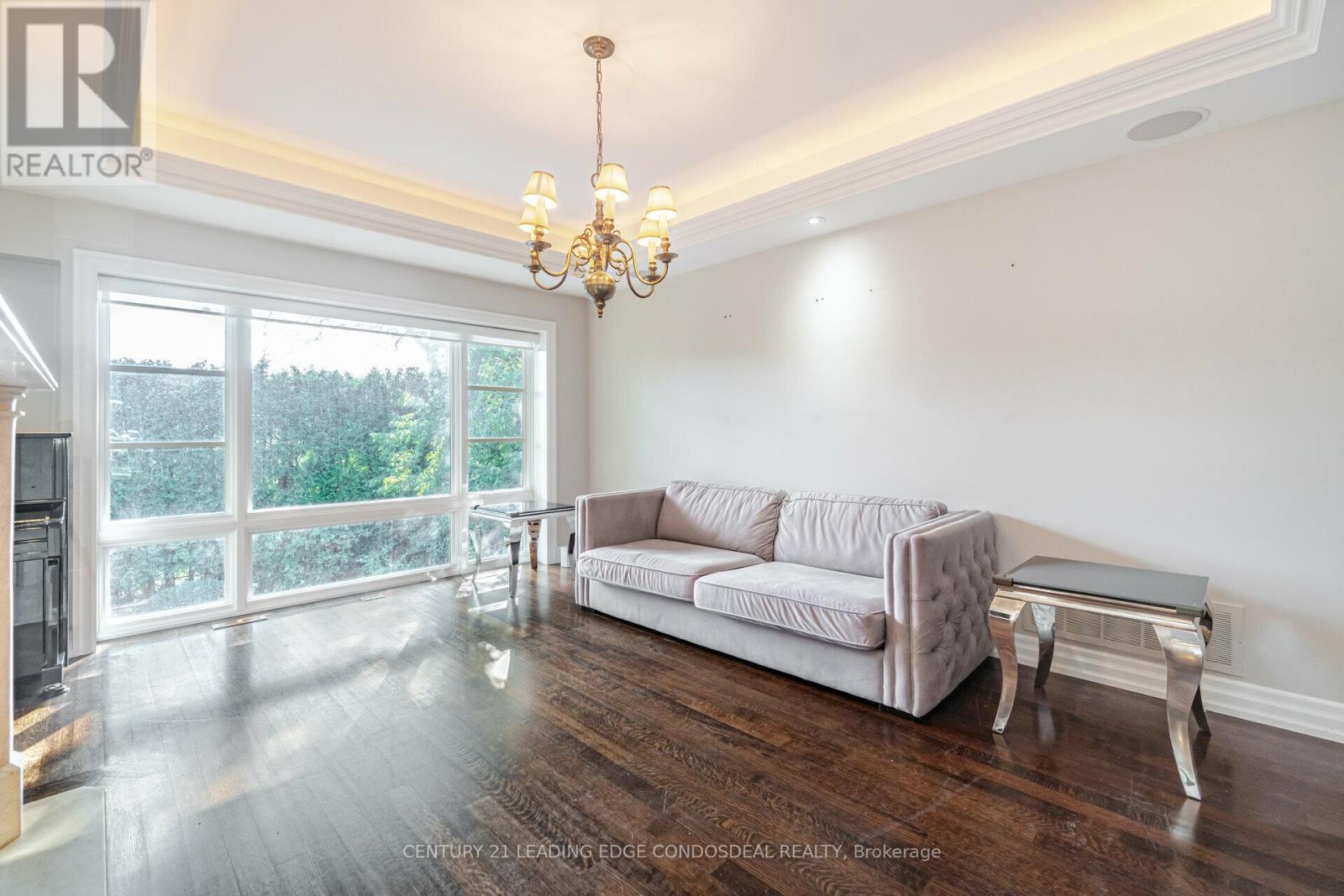 A living room with a grey couch and a chandelier.