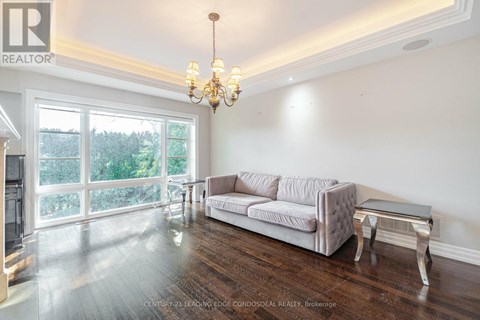 A living room with a grey couch and a chandelier.