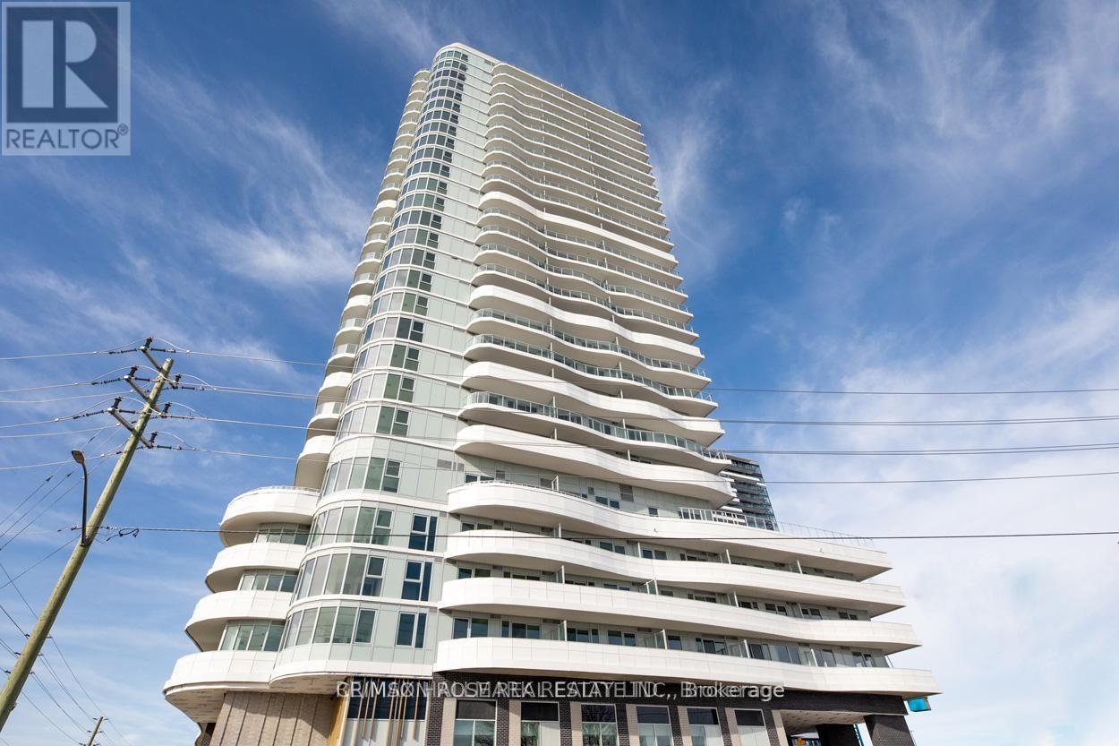 A tall white building with many windows and balconies is under a blue sky.