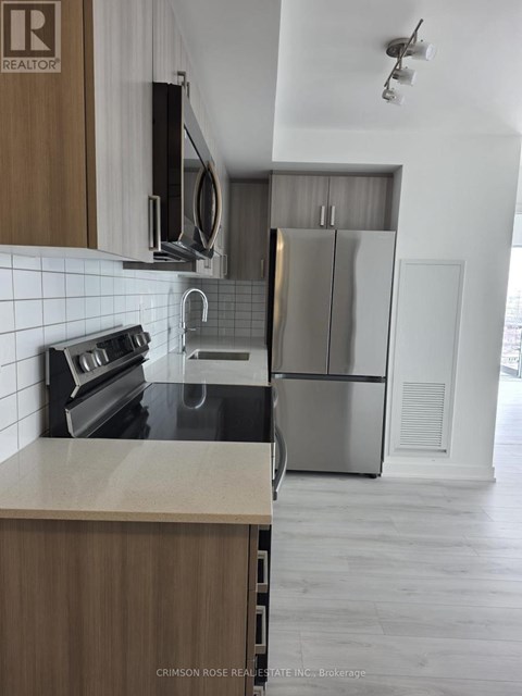 A kitchen with a refrigerator, microwave, and oven.