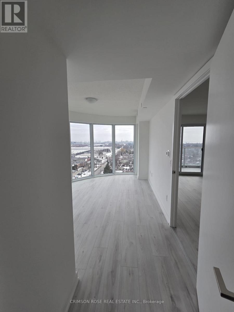 A hallway with wood floors and a view of the city through the windows.