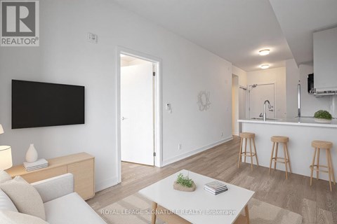 A living room with a white couch and a television mounted on the wall.