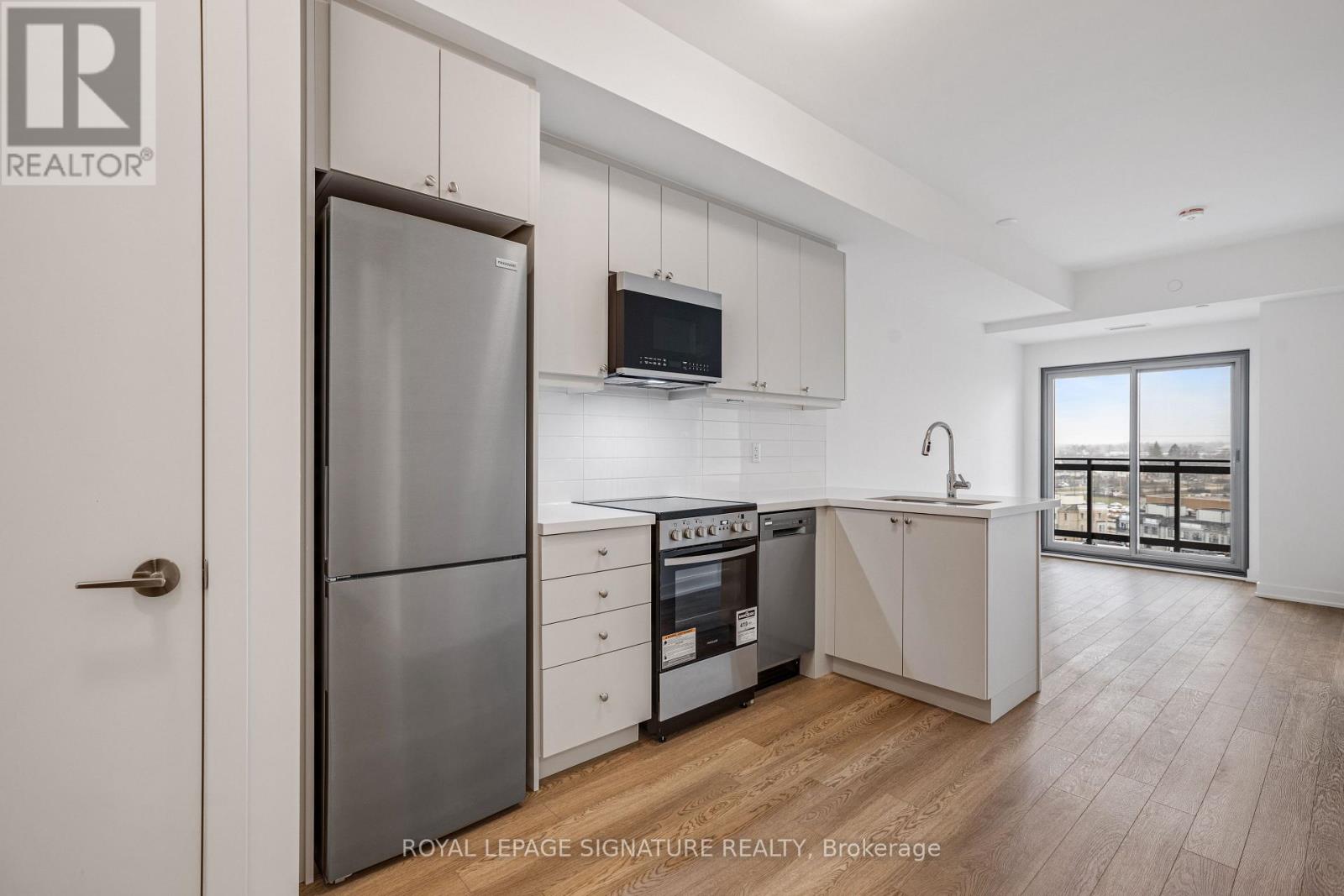 A modern kitchen with white cabinets and a wooden floor.