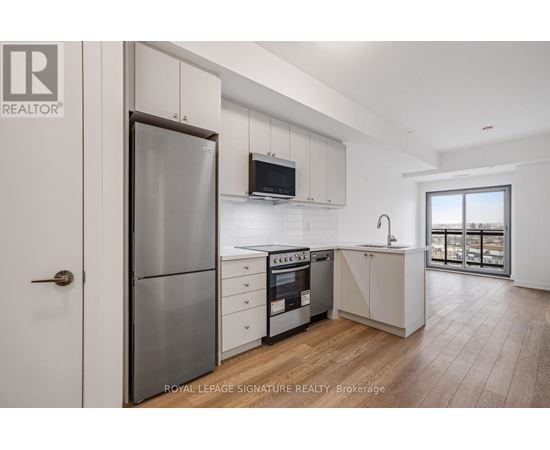 A modern kitchen with white cabinets and a wooden floor.