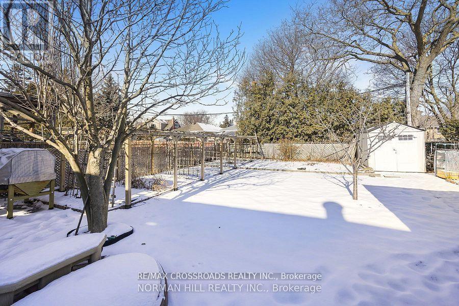 A snow-covered yard with a fence and trees.