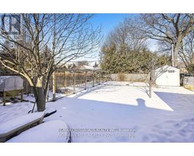 A snow-covered yard with a fence and trees.