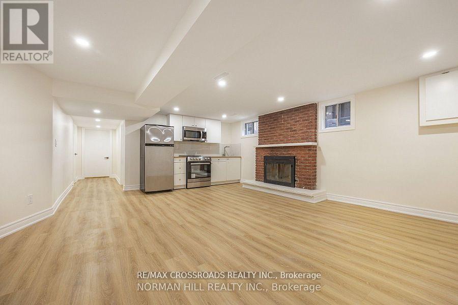A spacious living room with a fireplace and a kitchen area in the background.