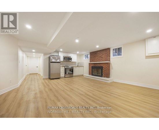 A spacious living room with a fireplace and a kitchen area in the background.