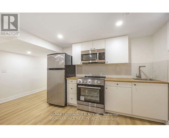 A kitchen with white cabinets and a stainless steel refrigerator.