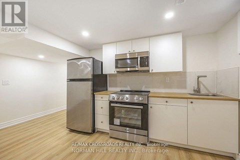 A kitchen with white cabinets and a stainless steel refrigerator.