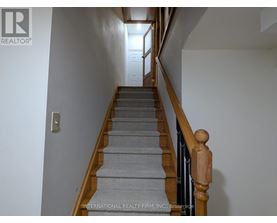 A staircase with a wooden handrail and grey carpeted steps.