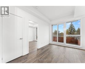 A room with a white door and a window with a view of trees outside.