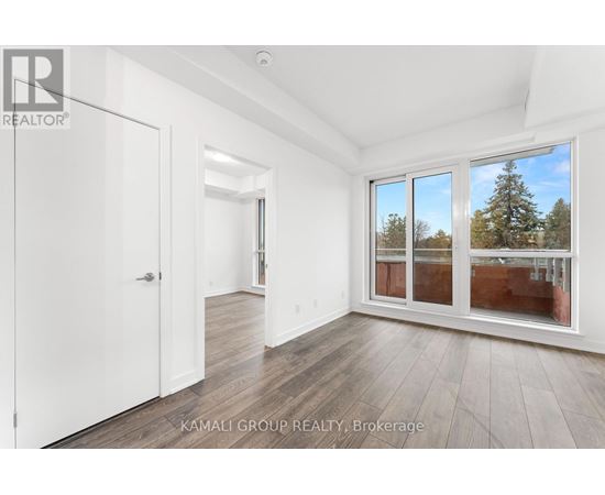 A room with a white door and a window with a view of trees outside.