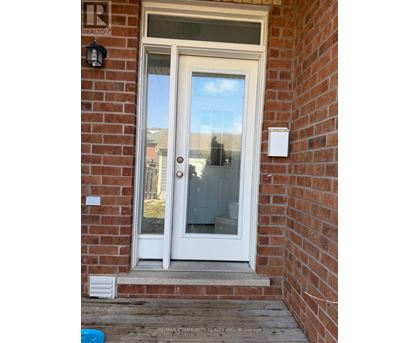 A white door with a glass window is set in a brick wall.