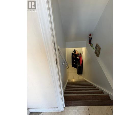 A staircase with a white wall and a red jacket hanging on the railing.