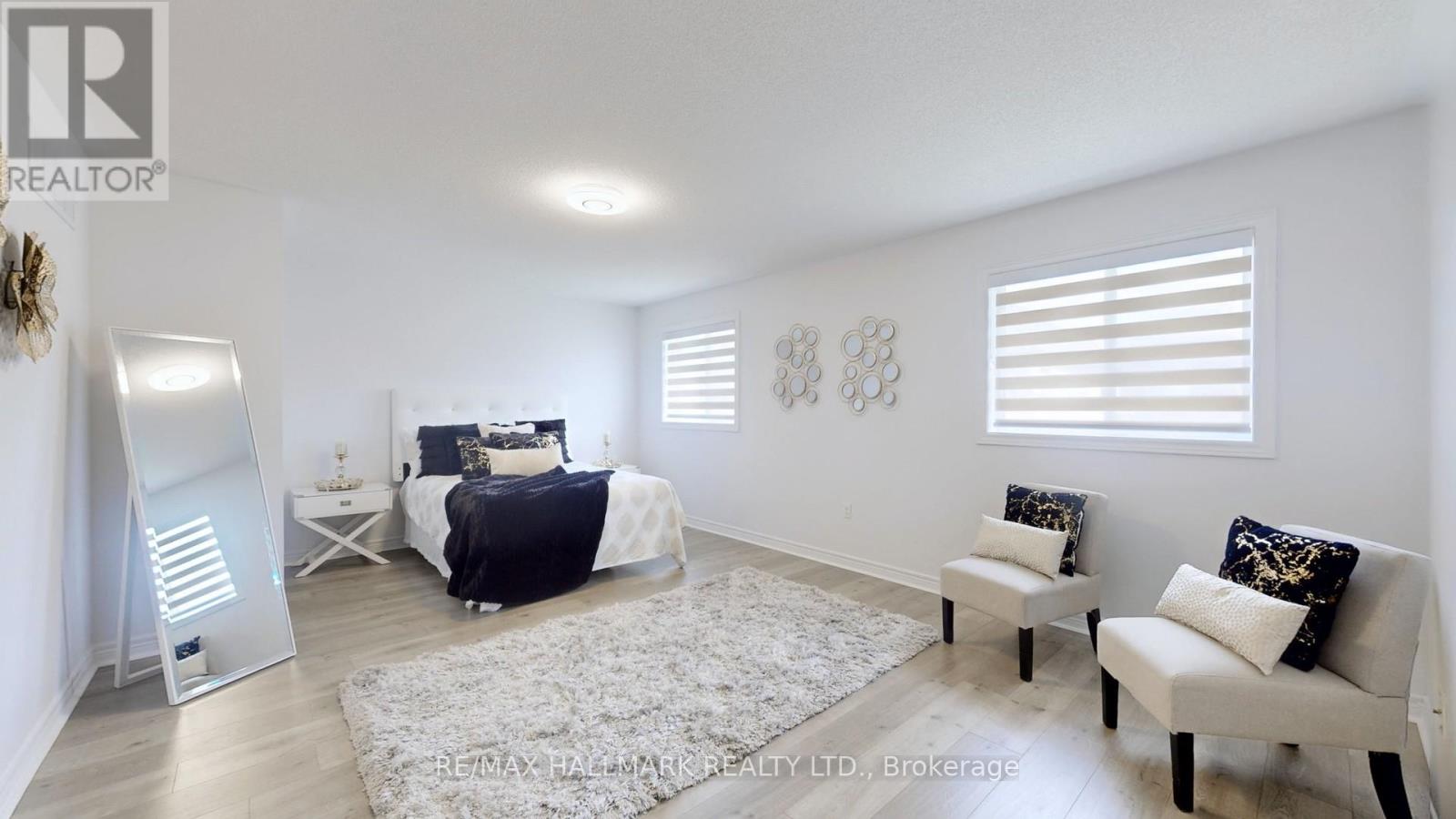 A bedroom with a bed, two chairs, and a rug.