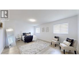A bedroom with a bed, two chairs, and a rug.