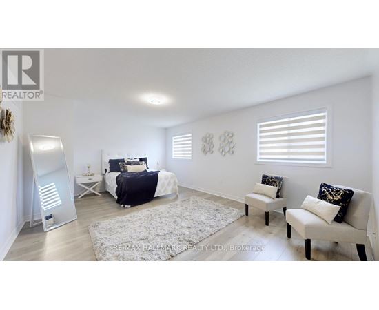 A bedroom with a bed, two chairs, and a rug.