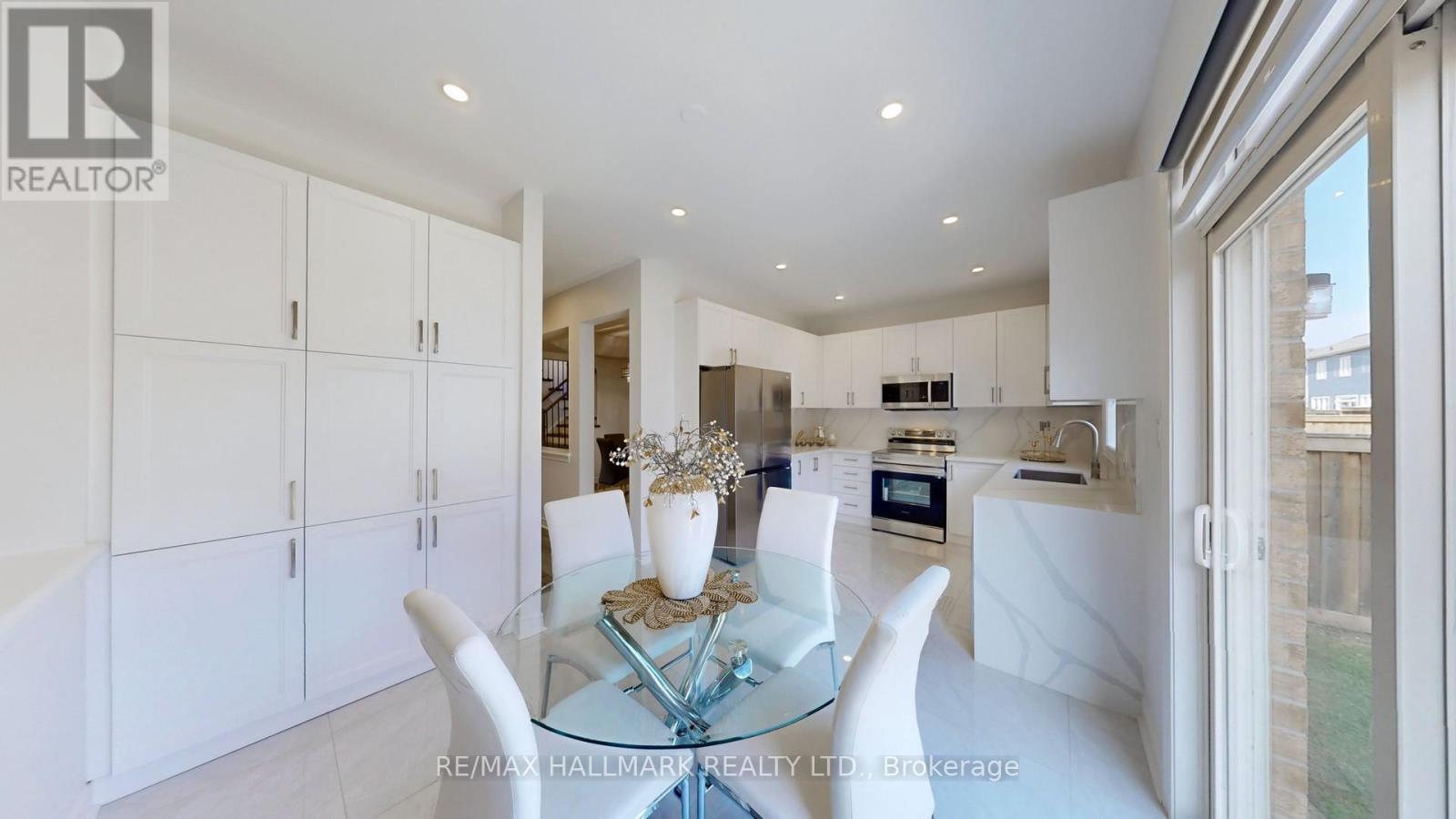 A modern kitchen with white cabinets and a glass dining table.