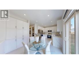 A modern kitchen with white cabinets and a glass dining table.