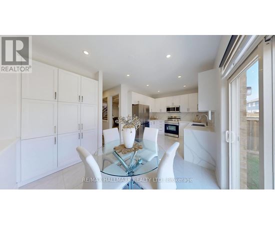 A modern kitchen with white cabinets and a glass dining table.