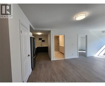 A spacious room with wooden flooring and white walls.