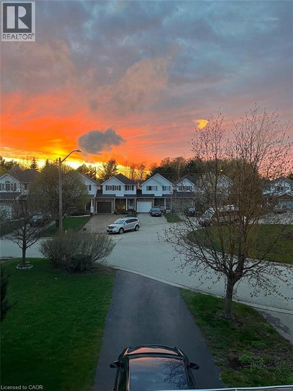A sunset view of a residential area with houses and cars.