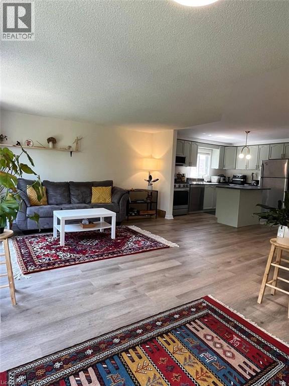 A living room with a grey couch and a rug with a pattern of letters and numbers.