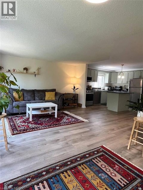 A living room with a grey couch and a rug with a pattern of letters and numbers.