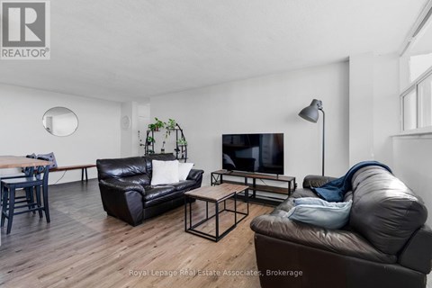 A living room with a black leather couch and a wooden floor.