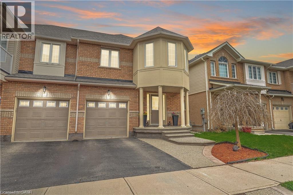A large, well-maintained house with a driveway and a tree in the front yard.